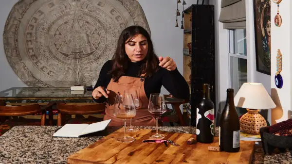Mujer explicando cómo ser sommelier, con copas de vino y botellas en una mesa.