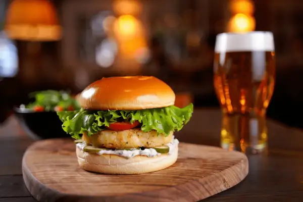 Deliciosa hamburguesa de pescado con lechuga, tomate y pepinillos, acompañada de una cerveza. ¿Cuánto tarda en descongelarse una hamburguesa?
