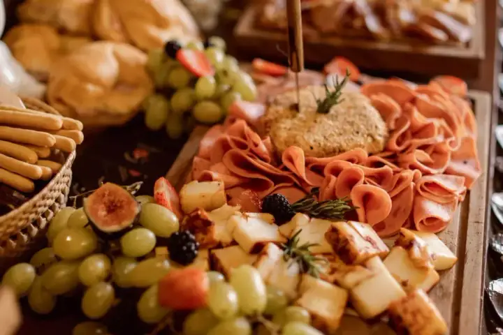 Un festín de quesos, embutidos, uvas, fresas y pan, un delicioso buffet para compartir.
